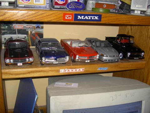 1988 Ford Bronco - Various model cars are displayed on a wooden shelf above a computer monitor.