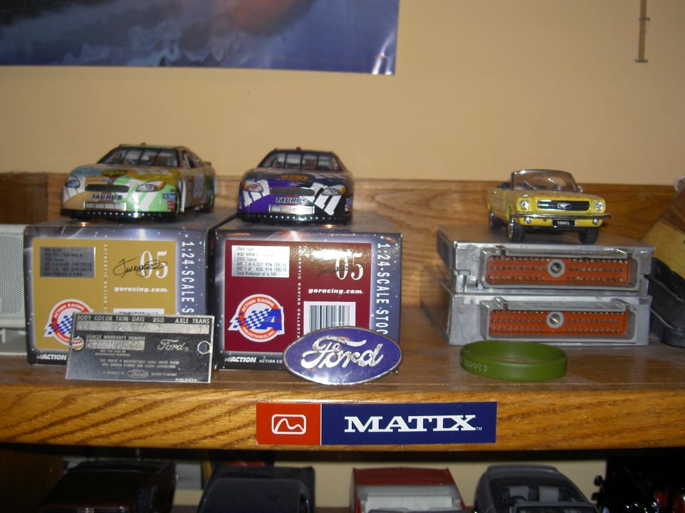 Shelf with Ford die-cast NASCAR Taurus models, Mustang model, Ford buckle, data plate and two EEC computers