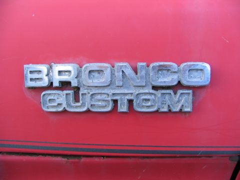 1978 Ford Bronco - The "BRONCO CUSTOM" emblem is visible on the red exterior of the vehicle.