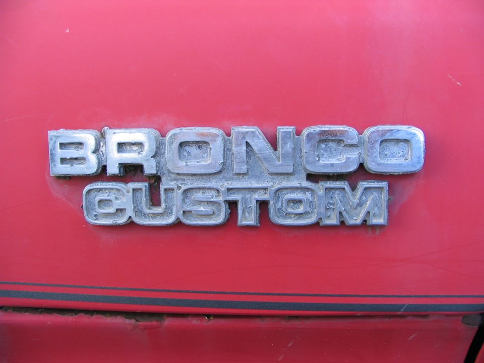 Close-up of a red vehicle's "BRONCO CUSTOM" badge