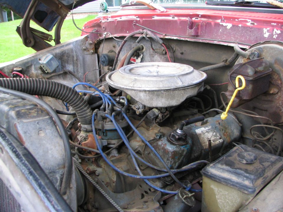 Engine bay with carburetor and distributor. Red paint visible