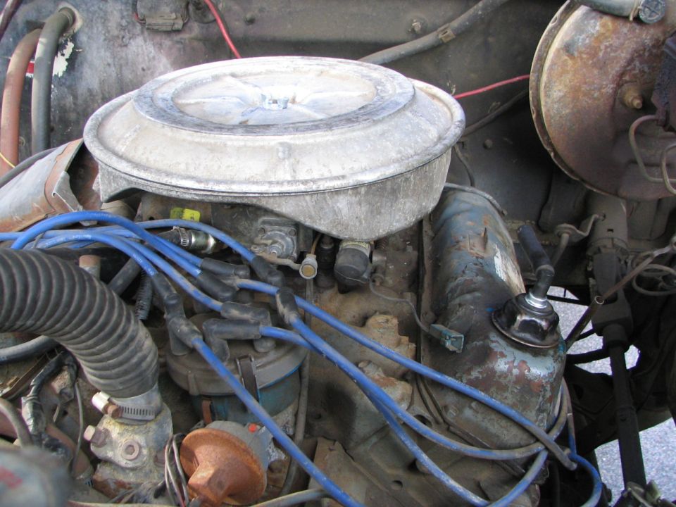 Engine bay detail showing air cleaner, distributor cap, and blue spark plug wires