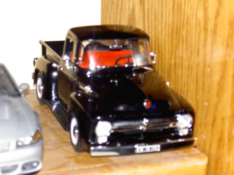 1988 Ford Bronco - This black 1955 Ford F-100 pickup truck features a vibrant red interior and is displayed next to another vehicle.