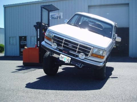 1995 Ford Bronco - White 1995 Ford Bronco with lifted suspension and aftermarket wheels parked in front of a warehouse.