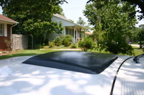 1994 Ford Bronco - Low-angle view across the white roof of a vehicle showing a smoked black acrylic sunroof wind deflector mounted ahead of the roof opening,…