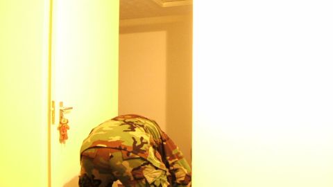 1988 Mercury Sable - A person wearing camouflage clothing bends over near a door with a teddy bear keychain.
