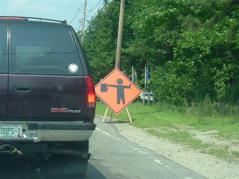 1966 Land Rover Discovery - A GMC SUV drives past a construction sign depicting a person holding a tool.