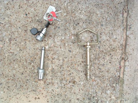 1993 Ford Bronco - A collection of trailer hitch parts, including a pin and ball mount, along with a set of keys, are laid out on a concrete surface.