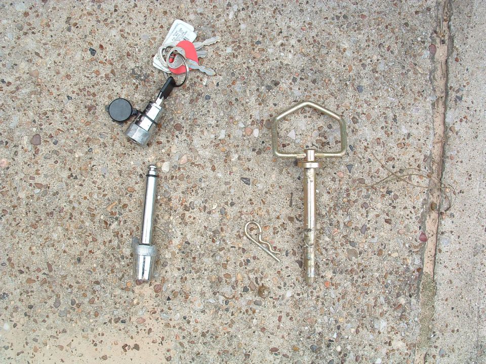 Locking and standard trailer hitch pins with keys and hairpin clip on concrete