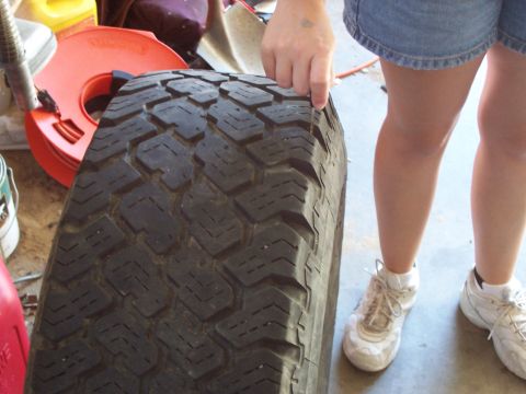 1991 Ford Bronco - A person is holding a tire, showing its tread pattern. Other items are in the background.