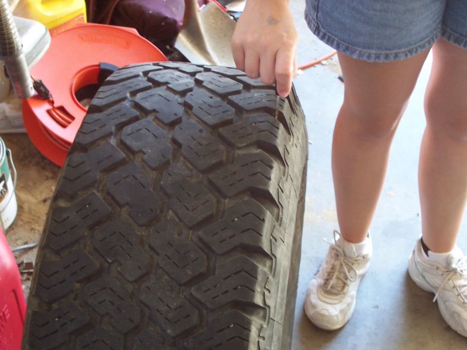 Close-up of a tire tread with a person's hand and legs visible