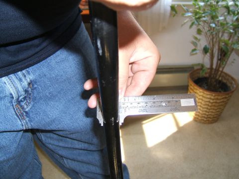 1998 Ford Taurus - A caliper is used to measure a black rod, with a potted plant visible in the background.