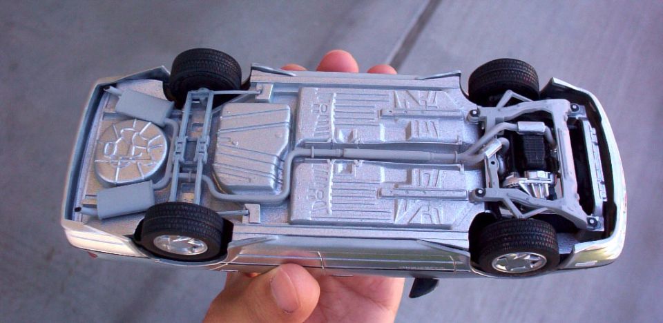Hand holding underside of a diecast car model showing molded chassis and suspension