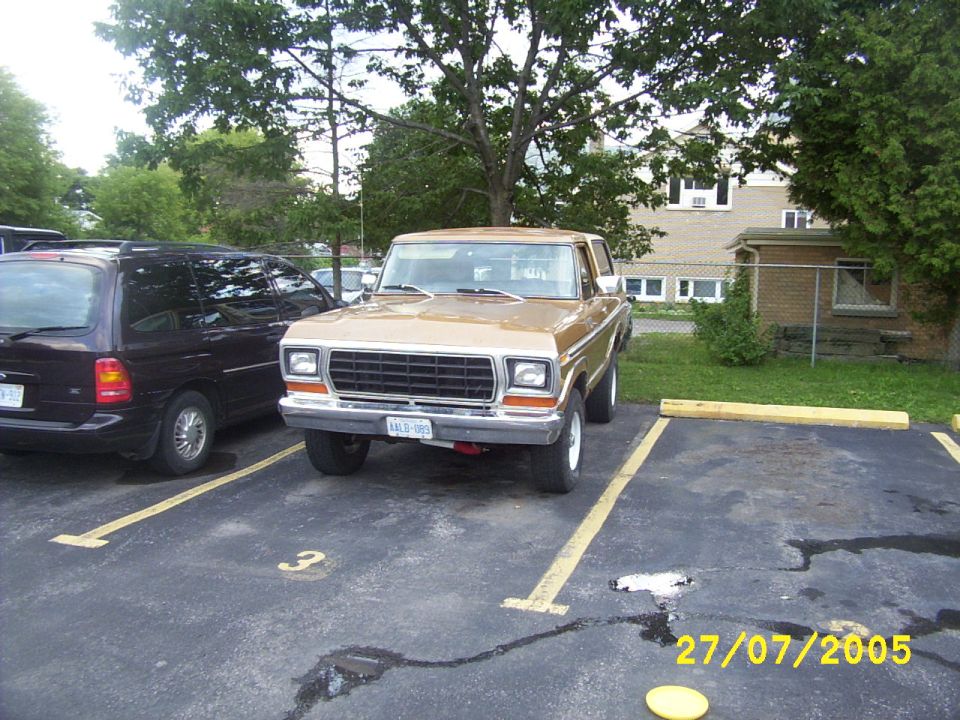 Front view of a tan 1979 Ford Bronco parked in a lot beside a dark minivan, dated 27/07/2005