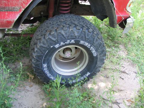 1978 Ford Bronco - A close-up view of a vehicle's off-road tire and suspension system, with visible text on the tire.