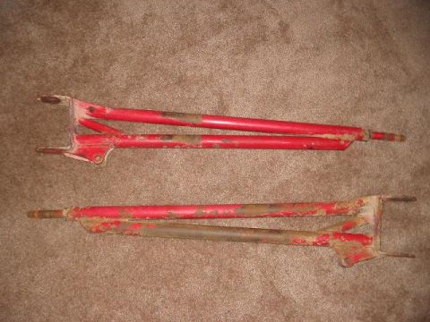 1991 Ford Bronco - Two red metal frames, possibly from a vehicle, are shown against a carpeted background.