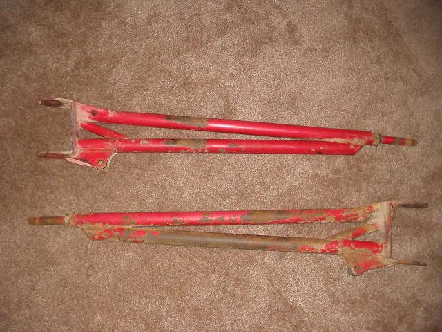 Two red metal frames with rust, lying on a brown carpet