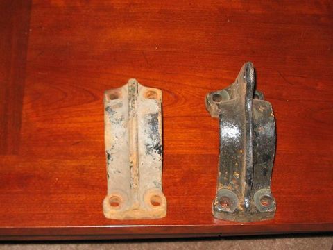 1991 Ford Bronco - Two aged metal hinges, one rusty and one painted black, rest on a polished wooden table.