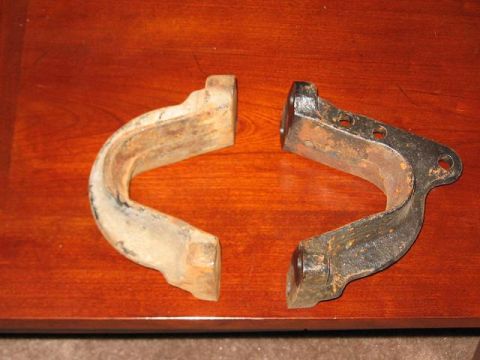 1991 Ford Bronco - Two C-shaped metal automotive parts, showing signs of rust, are displayed on a wooden table.