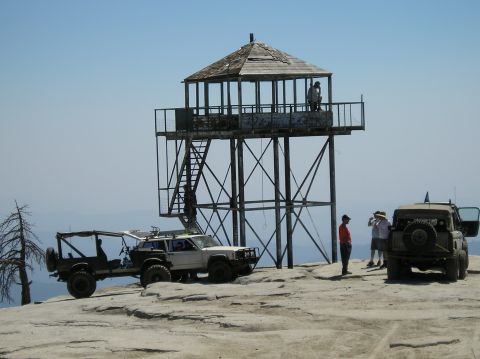 1967 Ford Bronco - Off-road enthusiasts gather at a remote fire lookout tower on a clear day.