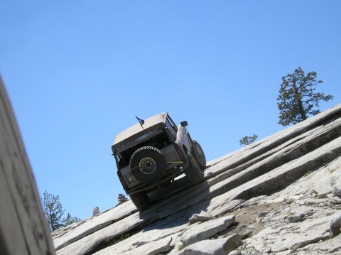 1967 Ford Bronco - 1967 Ford Bronco tackling a challenging off-road trail on a sunny day.