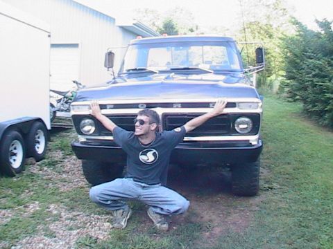 1977 Ford F-250 - A man poses in front of a blue Ford F-Series truck, with a trailer to the left.