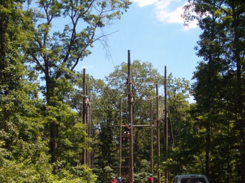 1995 Ford Bronco - An outdoor adventure park features tall wooden poles with ropes and ladders for participants to climb.