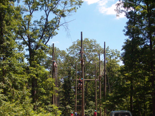 Obstacle course with people climbing wooden poles and ropes
