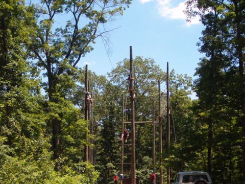1995 Ford Bronco - People navigate a ropes course set up with tall wooden poles and ropes.