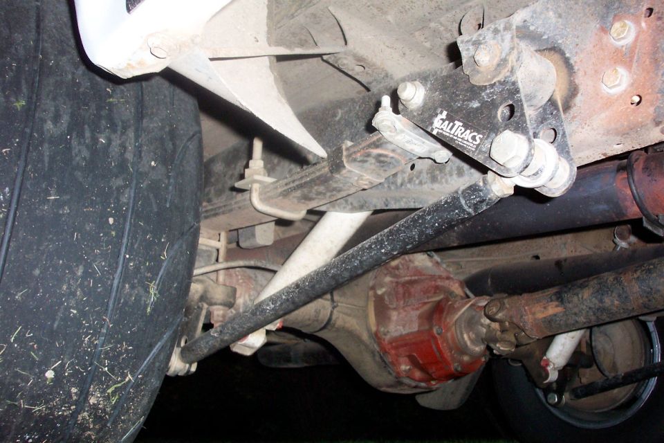 Truck underside showing CalTracs traction bar, leaf spring, red differential and driveshaft