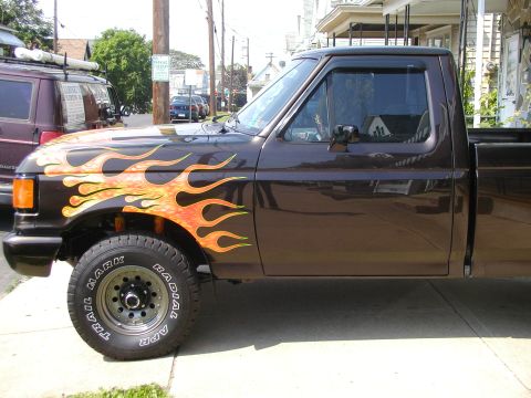 1991 Ford F-150 - This pickup truck features flame graphics on its side, with a visible "SUPERMOTORS.NET" watermark at the bottom right.