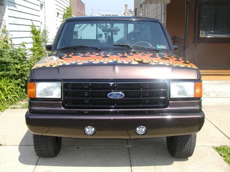 Brown 1991 Ford F-150 front view with orange and yellow flame decals on the hood
