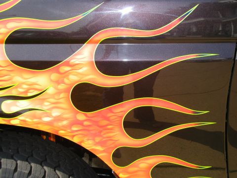 1991 Ford F-150 - Flame graphics cover the side of a dark-colored vehicle, with a tire visible below.