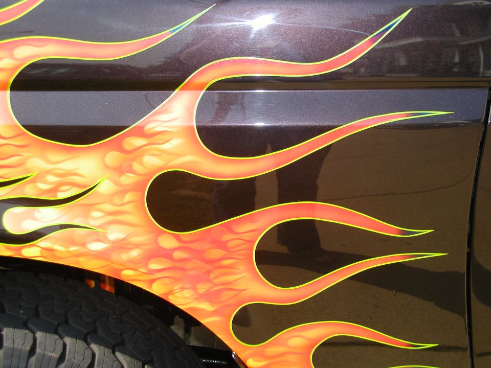 close-up of flame graphics on a dark vehicle side panel, showing tire tread