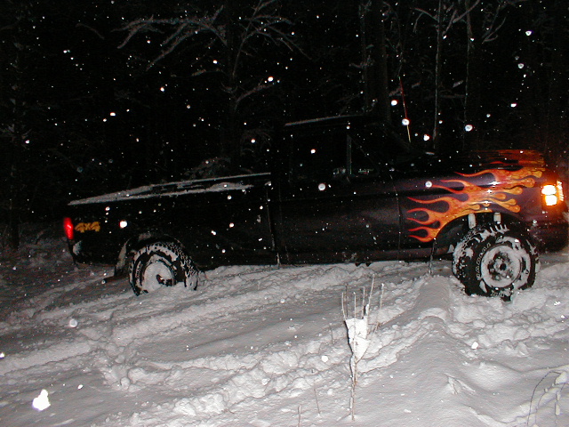 1991 Ford F-150 with flame decals stuck in deep snow at night