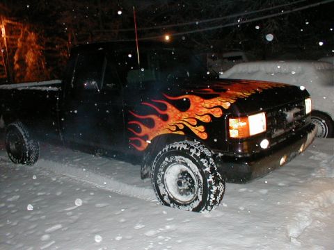1991 Ford F-150 - A black pickup truck with flame decals sits in the snow at night.