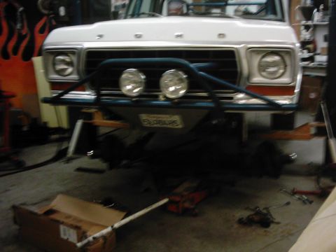 1978 Ford Bronco - The front of a 1978 Ford Bronco is shown, lifted on jack stands in a garage.