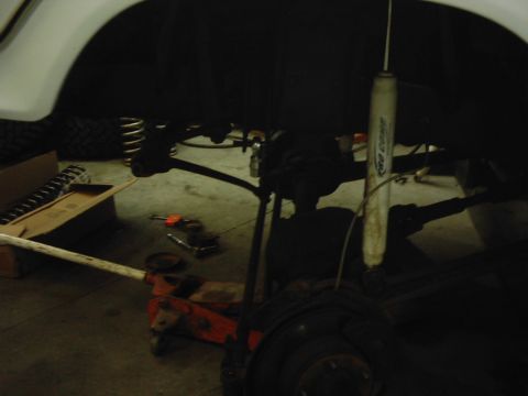 1978 Ford Bronco - Underneath view of vehicle suspension components and a floor jack.