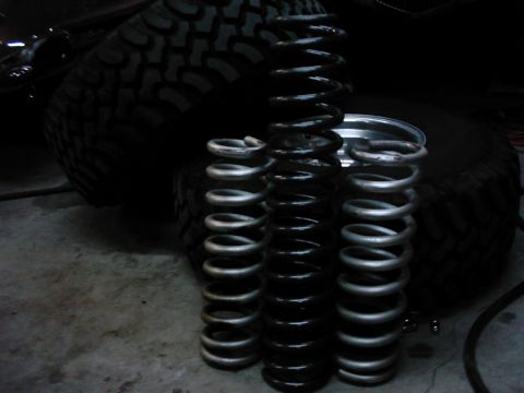 1978 Ford Bronco - A collection of coil springs are displayed next to a large off-road tire, with a Supermotors.net watermark in the corner.