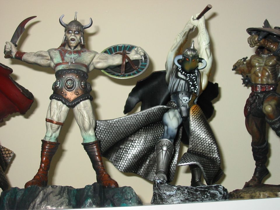 Three fantasy action figures with swords and shields on display bases