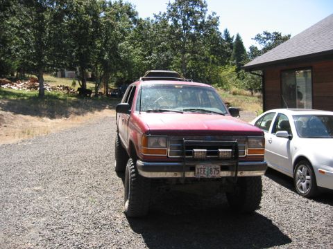 1991 Ford Explorer - A red 1991 Ford Explorer is parked on a gravel driveway next to a white sedan.