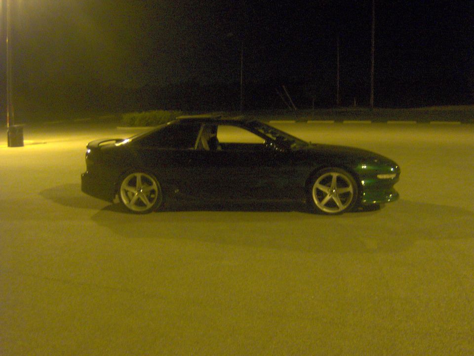 Dark green 1994 Ford Probe coupe, side view, parked at night