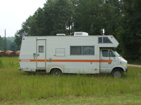 1966 Ford Ranchero - A Midas RV motorhome is seen parked in a field with trees in the background.