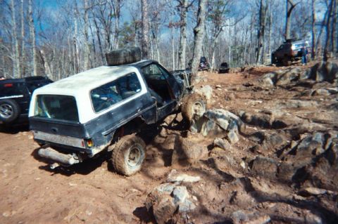 1985 Ford Bronco - This SUV is navigating a rocky trail, with other vehicles visible in the background.