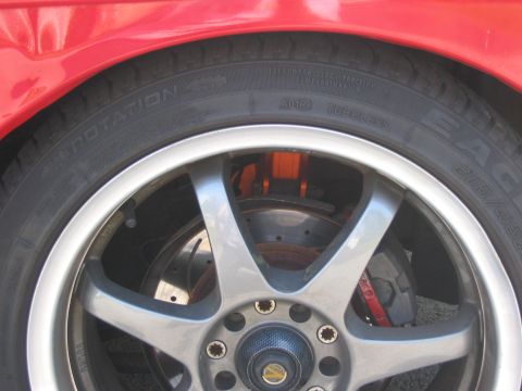 1994 Ford Probe - Close-up of a red car's wheel a silver five-spoke rim and visible orange brake calipers.