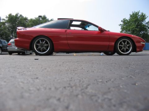 1994 Ford Probe - A red coupe with a spoiler and sunroof is seen from the side in a parking lot.