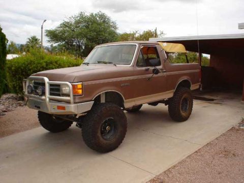 1989 Ford Bronco - This lifted Ford Bronco features a custom front bumper and a removable soft top, suggesting a model year prior to 1992.