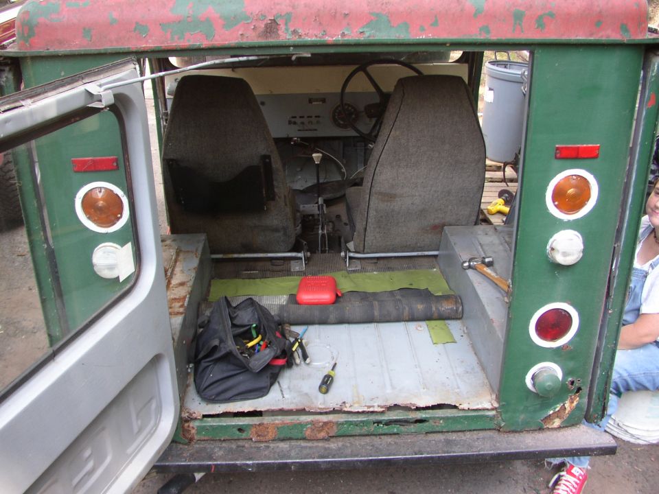 Green 1973 Jeep CJ5 interior with worn seats, steering wheel, and floor tools