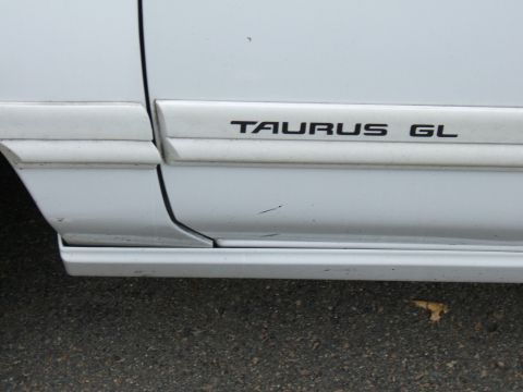 1998 Ford Taurus - Close-up of the side door trim on a white vehicle, showing the 'TAURUS GL' badging.