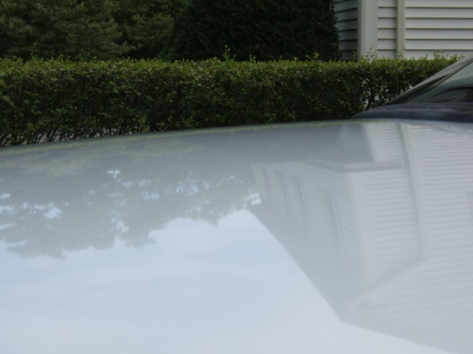 Reflection of a house on a white car hood